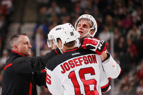 Jon Merrill #34 is helped off of the ice by his New Jersey Devils teammates