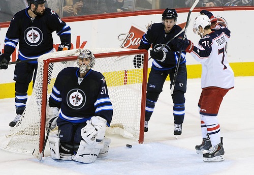 WINNIPEG, MB - JANUARY 11: Goaltender Ondrej Pavelec #31 of the Winnipeg Jets kneels in the net as Nick Foligno #71 of the Columbus Blue Jackets celebrate a second period goal at the MTS Centre on January 11, 2014 in Winnipeg, Manitoba, Canada.  (Photo by Lance Thomson/NHLI via Getty Images)