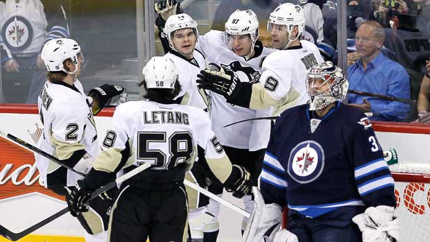 Winnipeg Jets goaltender Ondrej Pavelec looks on as Sidney Crosby celebrates with his teammates after a goal during a game on Friday, January 15, 2013. (Photo by John Woods/Canadian Press)